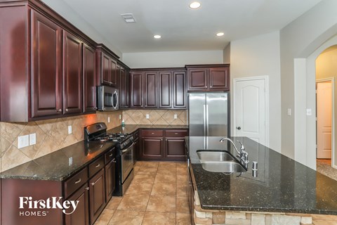 A kitchen with dark brown cabinets and a black countertop.