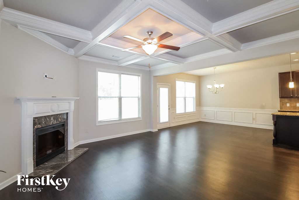 an empty living room with a fireplace and a ceiling fan