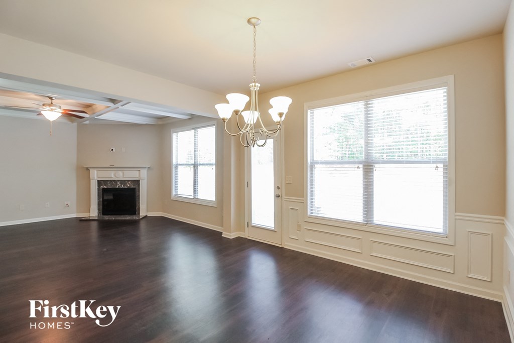 an empty living room with a fireplace and large windows