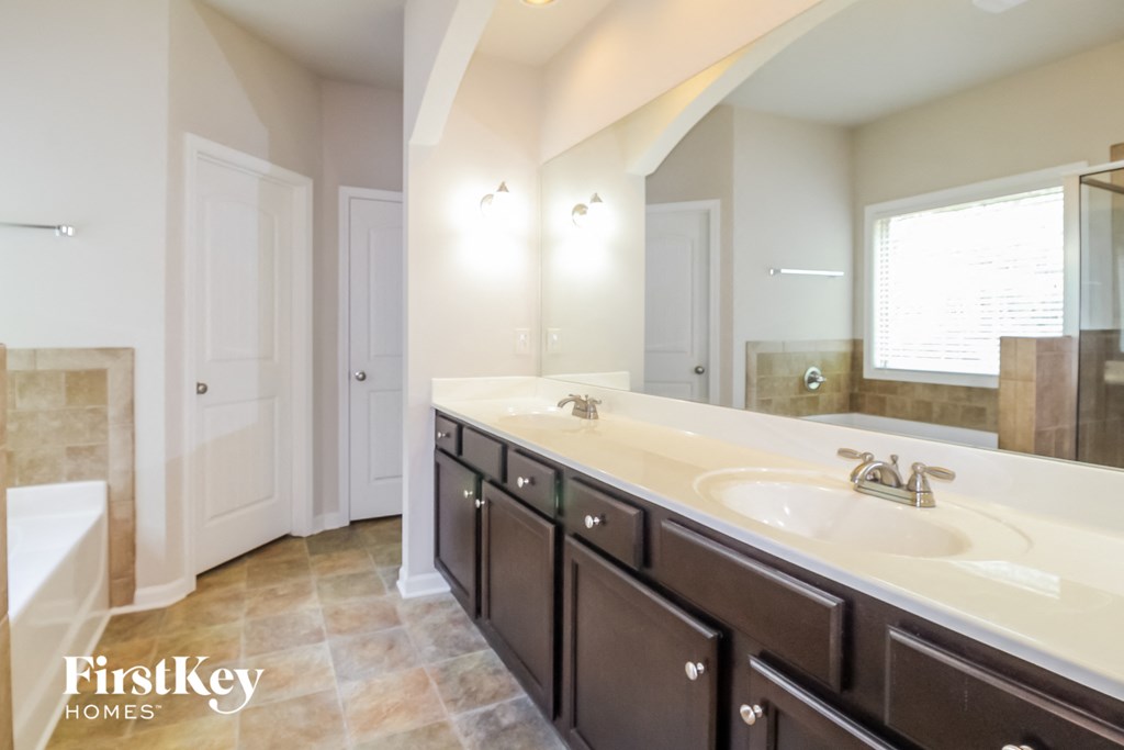 the master bathroom has a large vanity with two sinks and a tub