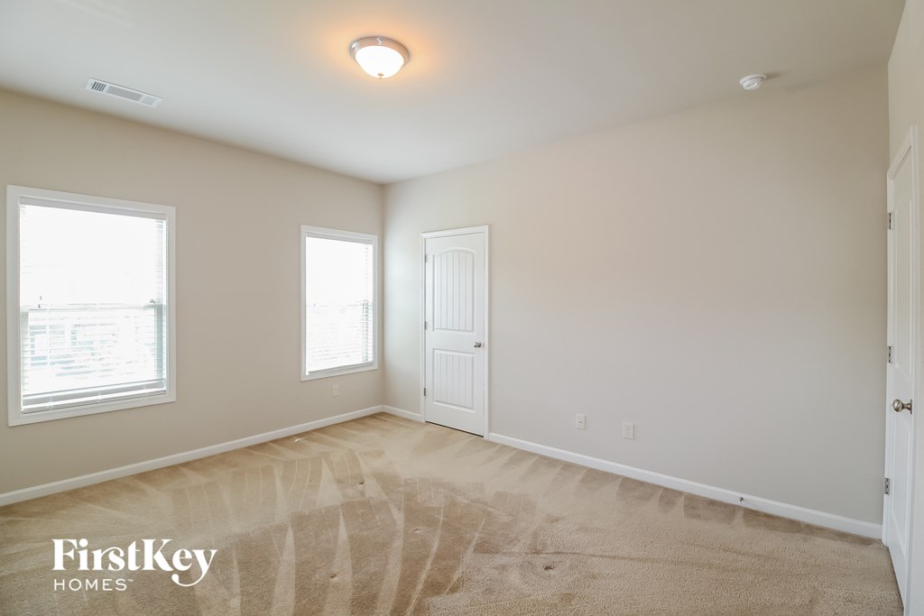 a bedroom with a carpeted floor and two windows