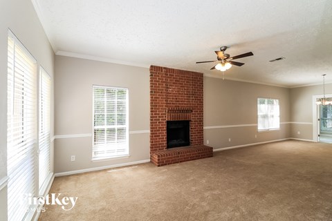 a living room with a brick fireplace and a ceiling fan