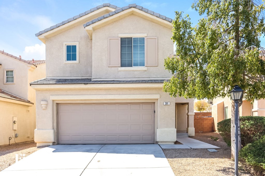 A house with a garage and a tree in front.