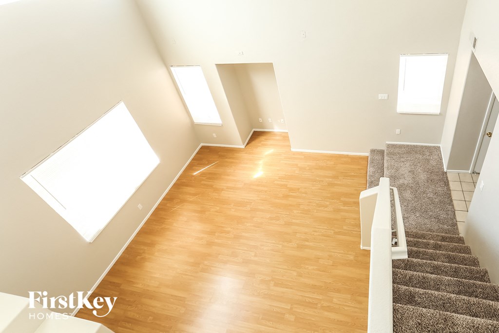 A spacious room with wooden floors and a staircase leading to another level.