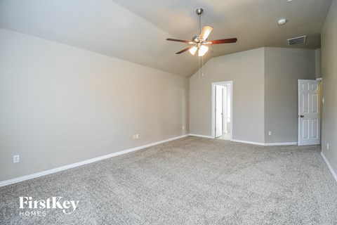 the spacious living room with ceiling fan and carpet