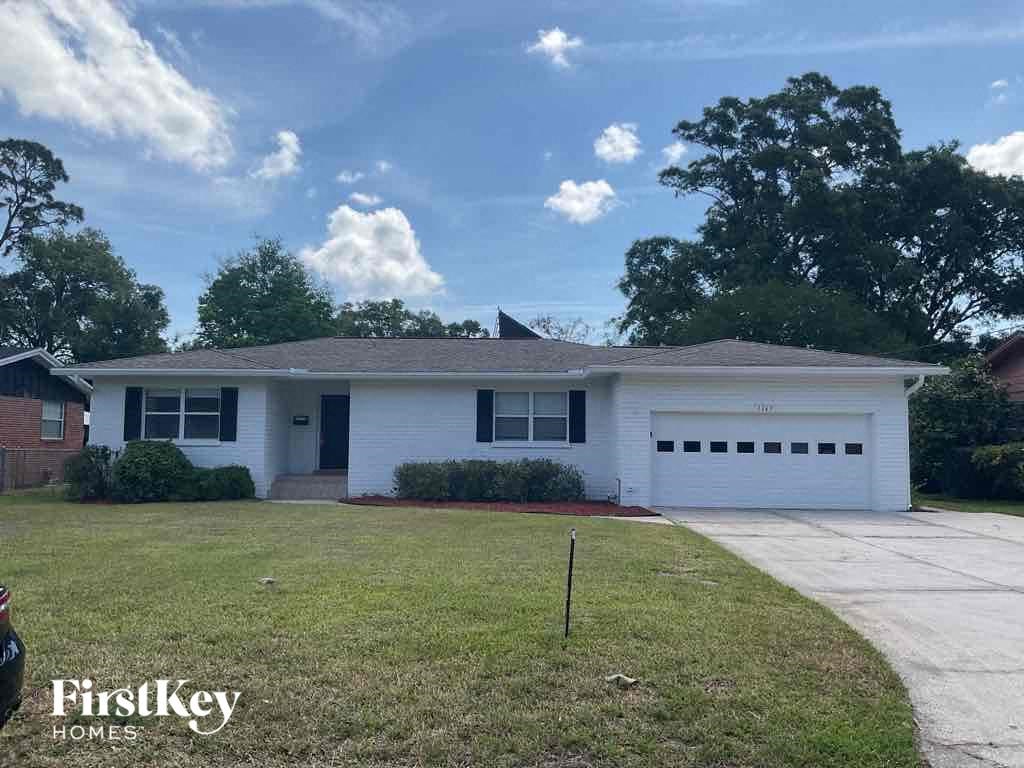 the front of a white house with a lawn and a driveway