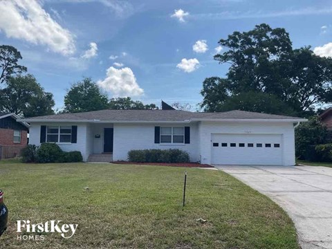 the front of a white house with a lawn and a driveway