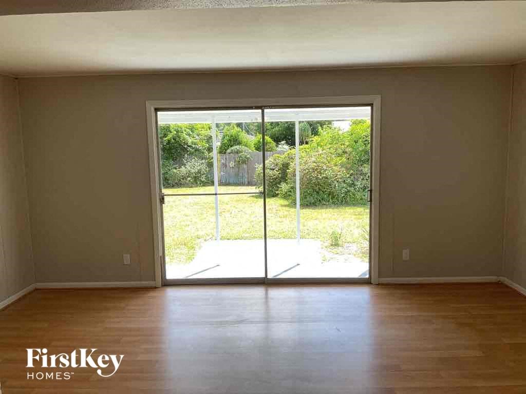 an empty living room with a wood floor and sliding glass doors