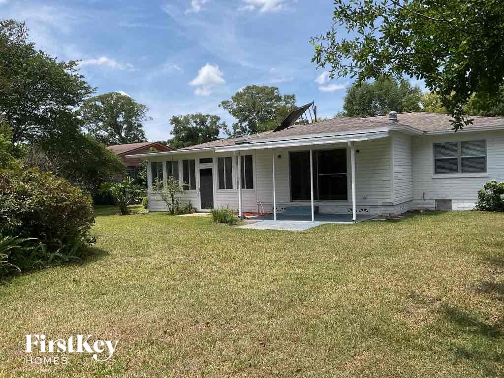 the front of a white house with a yard and grass