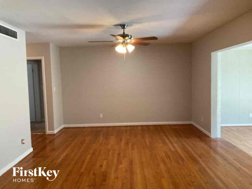 an empty living room with wood floors and a ceiling fan