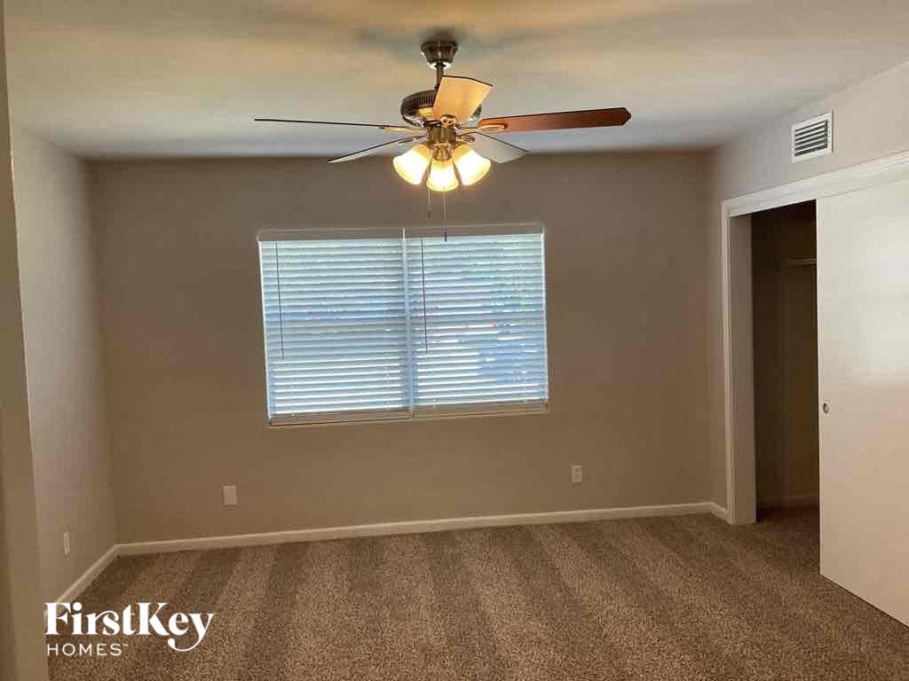 an empty bedroom with a ceiling fan and a window