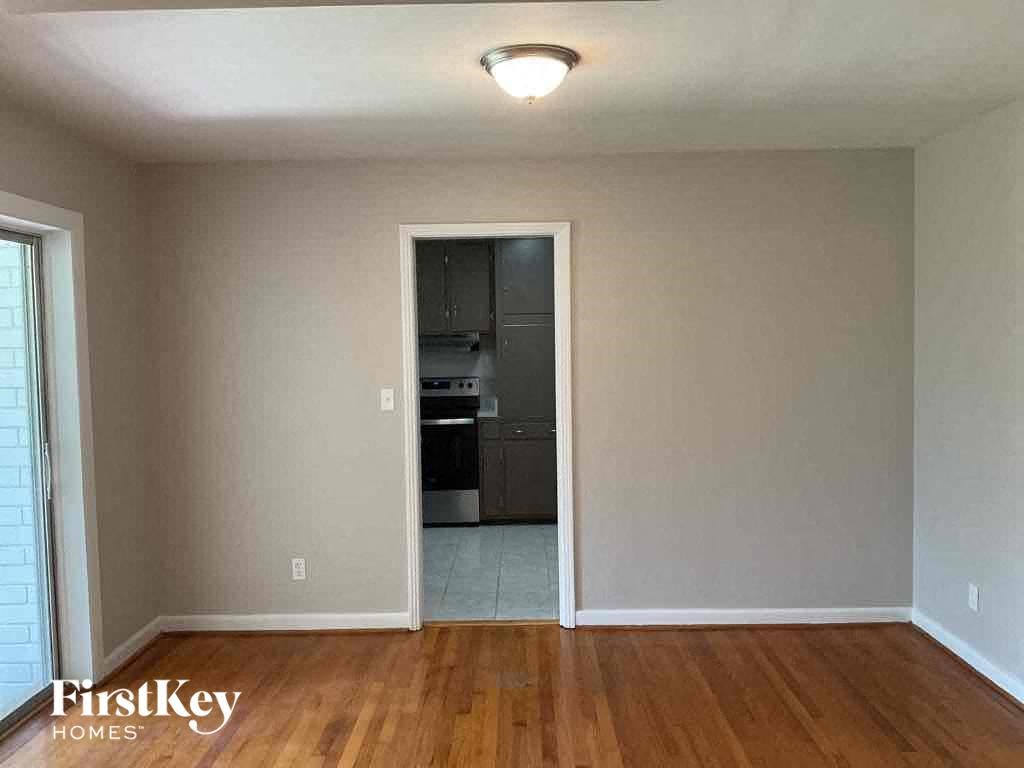an empty living room with wooden floors and a doorway to a kitchen