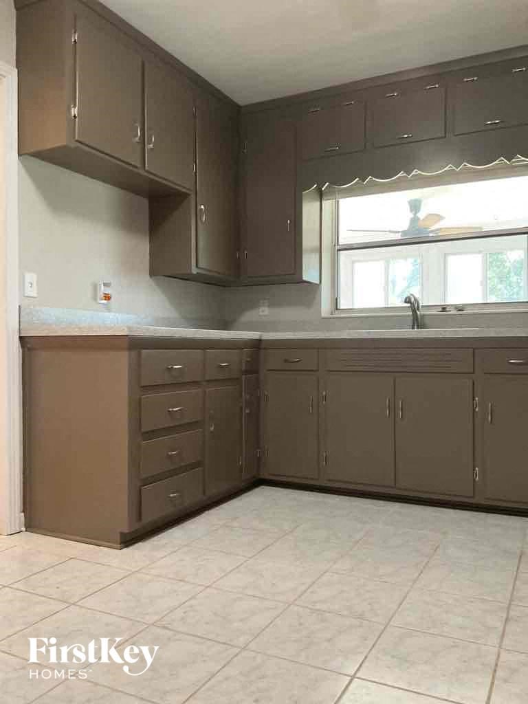 an empty kitchen with brown cabinets and a window
