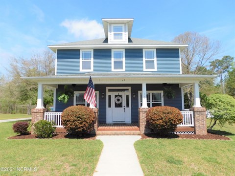A blue house with a flag on the front porch.