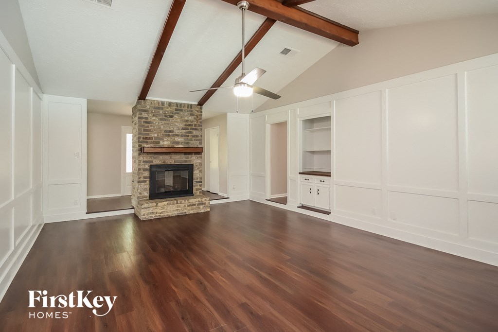 A spacious room with a stone fireplace and wooden floors.