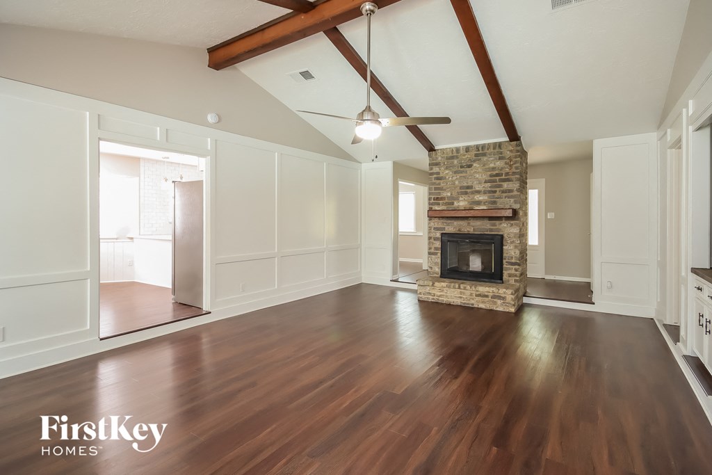 A spacious living room with wooden floors and a stone fireplace.