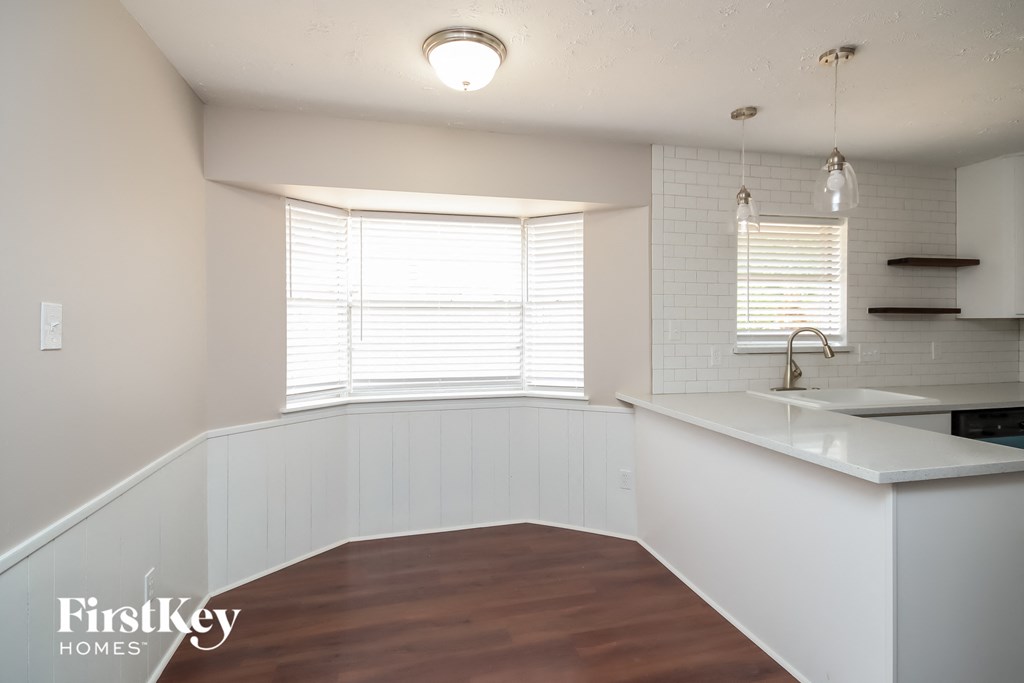 A kitchen with white cabinets and a wooden floor.