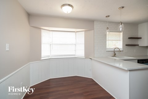 A kitchen with white cabinets and a wooden floor.