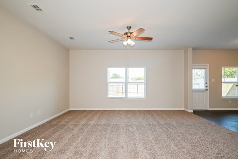 an empty living room with a ceiling fan and a carpet