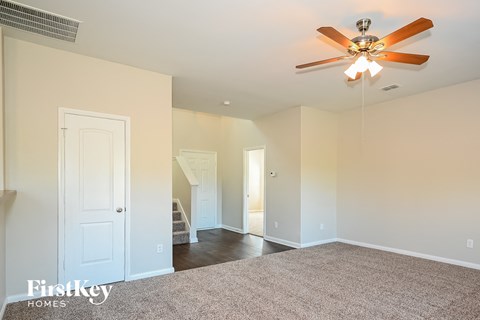 a living room with a ceiling fan and a carpet