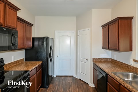 a kitchen with brown cabinets and black appliances and a white door