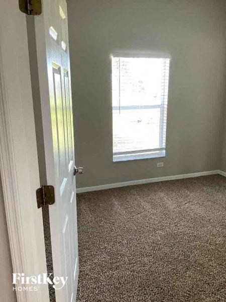 A room with a carpeted floor and a window with blinds.