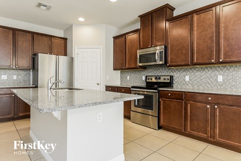 A kitchen with brown cabinets and a marble countertop.