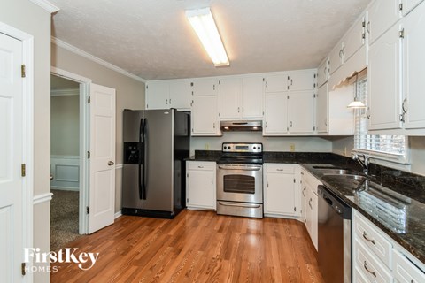 A kitchen with wooden floors and white cabinets.