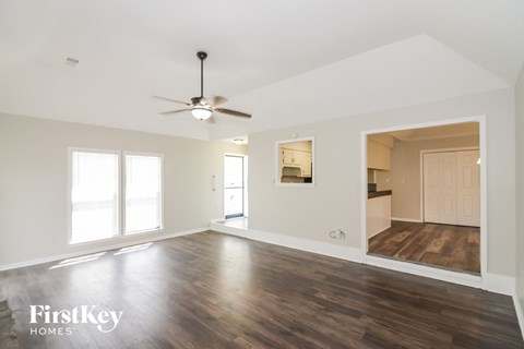 A spacious room with a ceiling fan and wooden flooring.