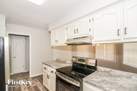 A kitchen with white cabinets and a black stove top oven.