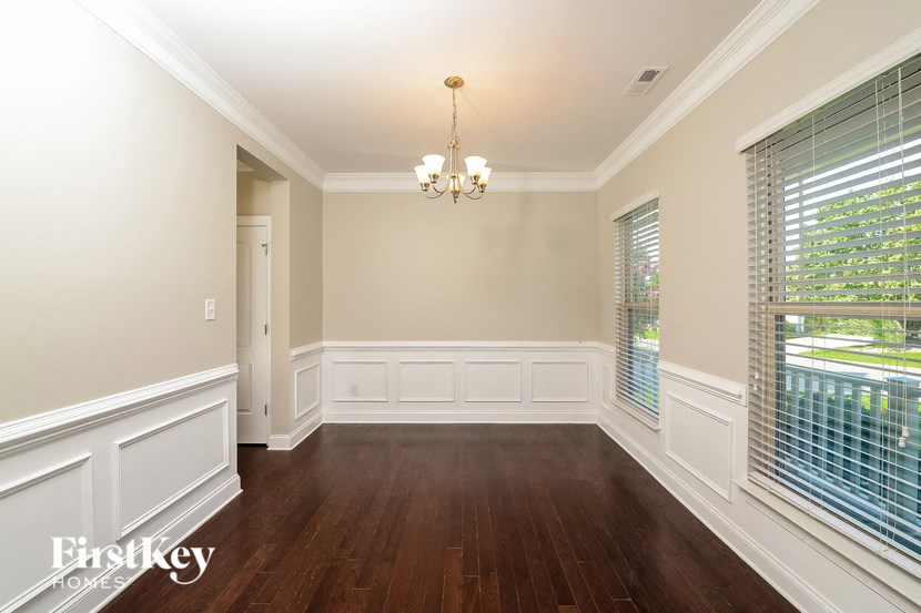 a dining room with white wainscoting and a large window
