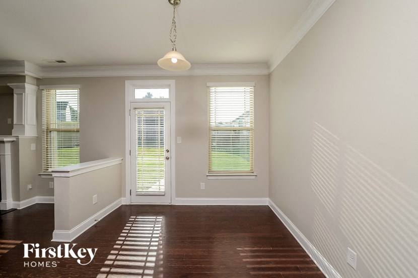 an empty dining room with windows and a door to the kitchen