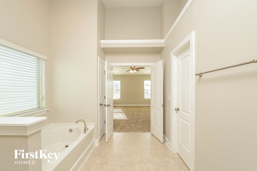 a master bathroom with a large tub and a shower and a door to a hallway
