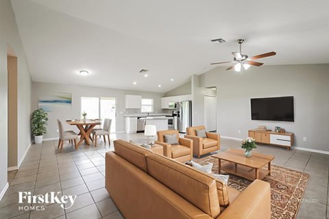 A spacious living room with a brown sofa and a ceiling fan.
