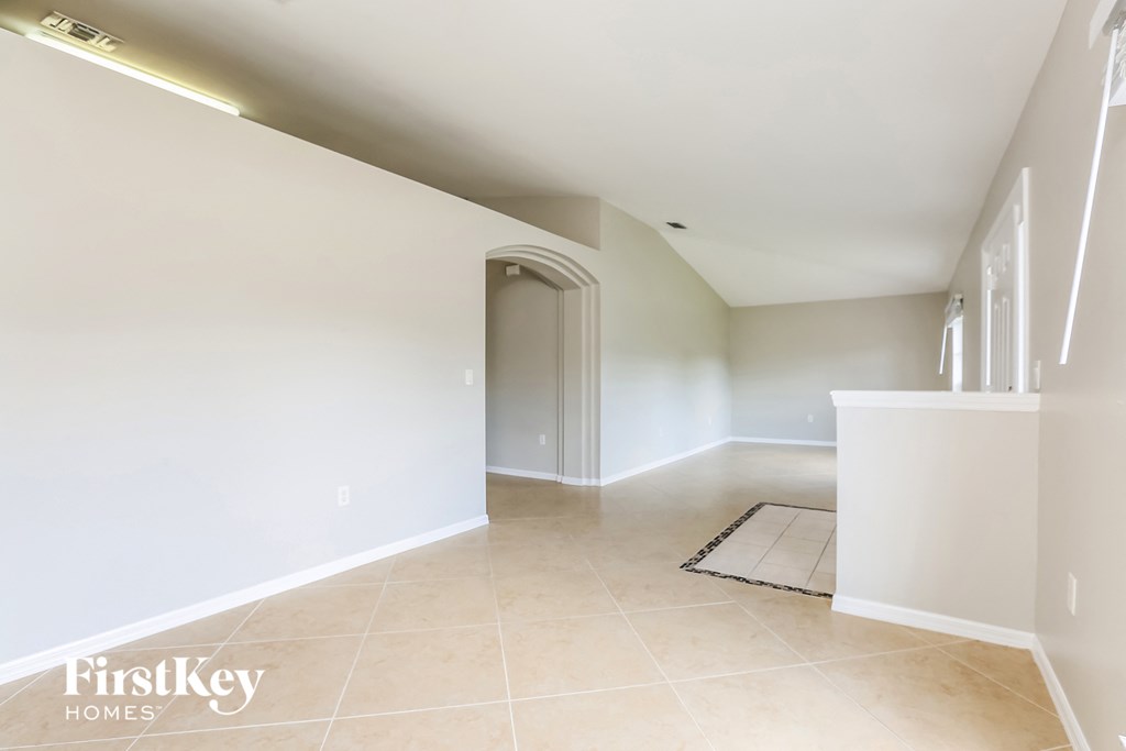 A spacious room with a doorway leading to another room and a rug on the floor.