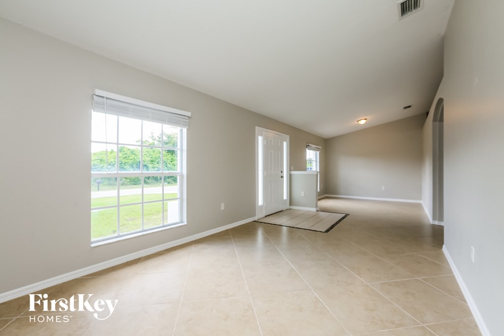 A spacious room with a large window and a door leading to a balcony.