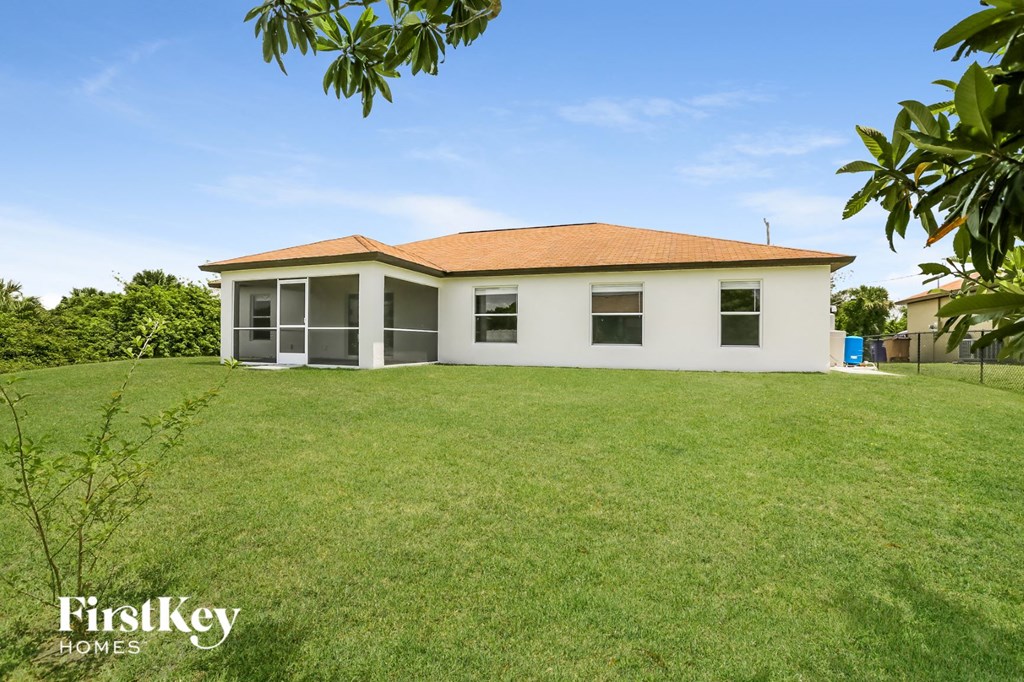 A white house with a brown roof is surrounded by green grass.