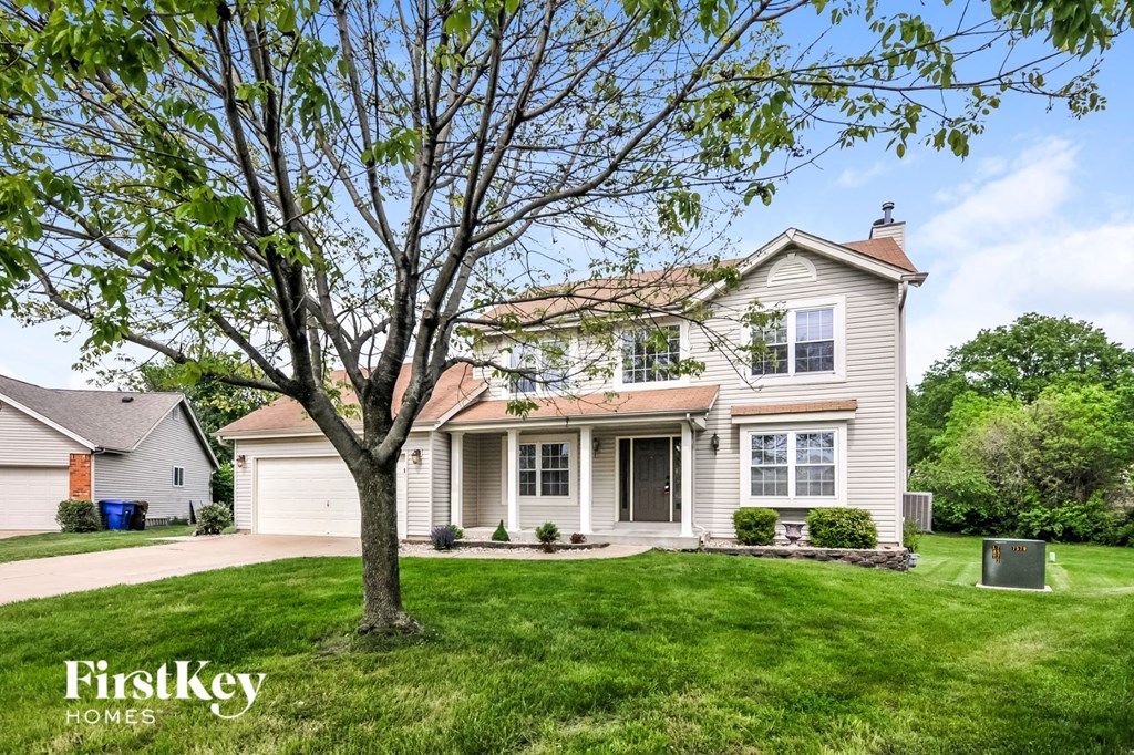 a white house with a large tree in the yard