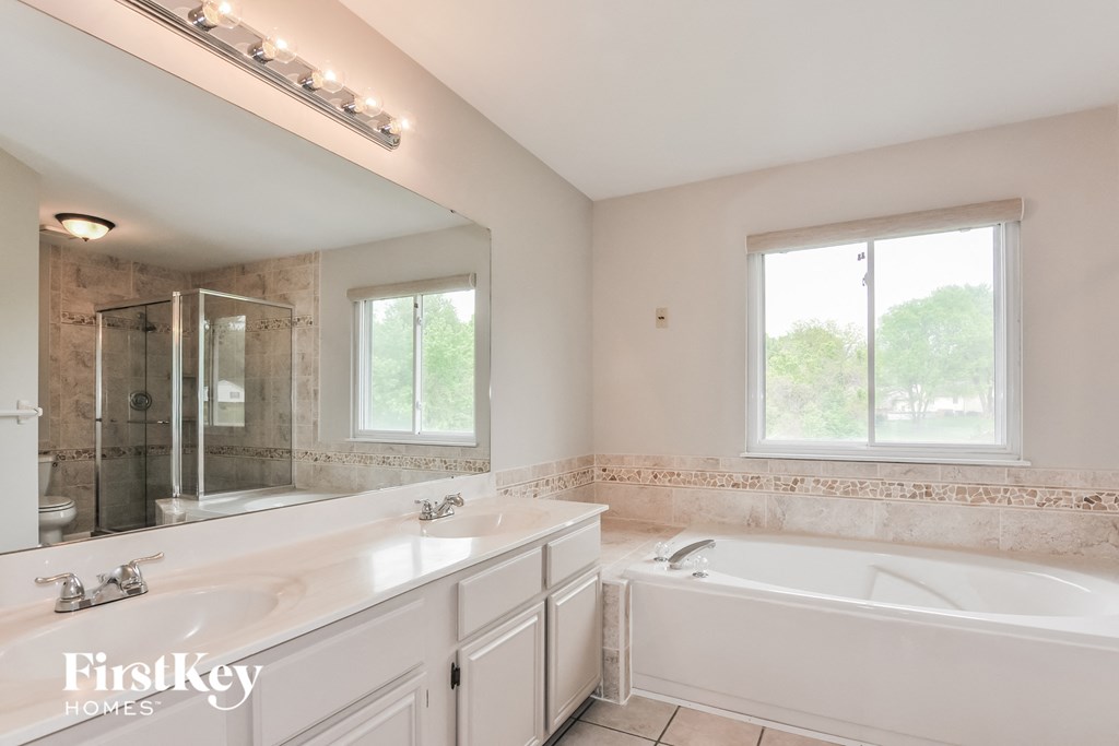 a white bathroom with a tub and a sink and a mirror
