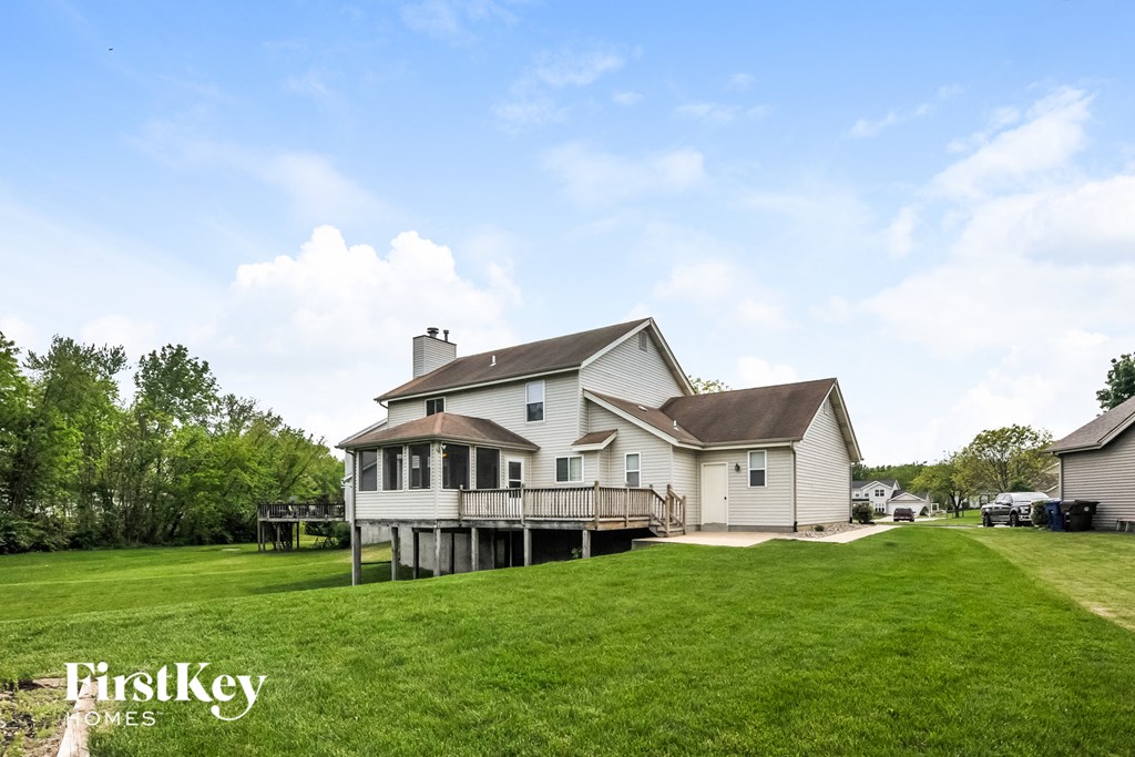 a large white house with a deck on top of a hill