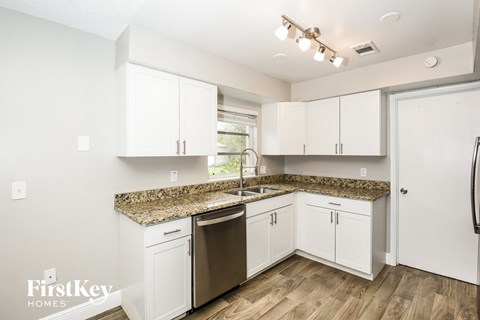 a kitchen with white cabinets and granite counter tops and a stainless steel sink