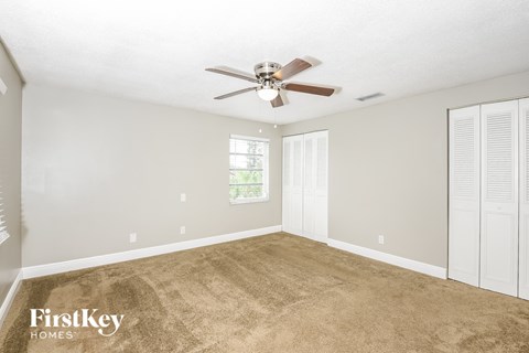 a living room with carpet and a ceiling fan