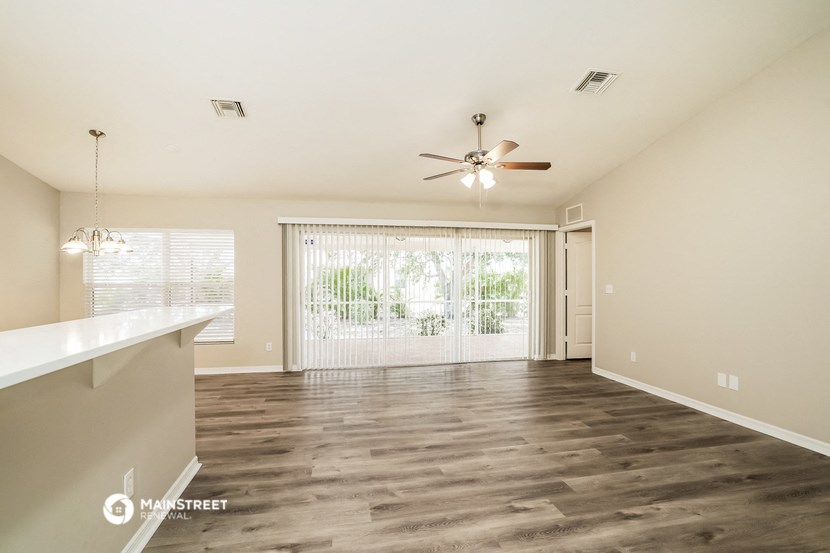 an empty living room with a ceiling fan and a window