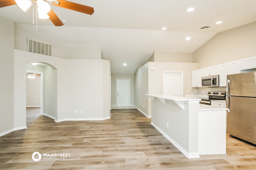 an open kitchen and living room with white walls and wood flooring