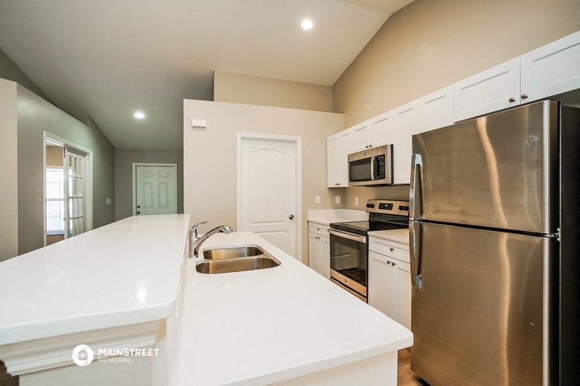 a large kitchen with stainless steel appliances and white counter tops