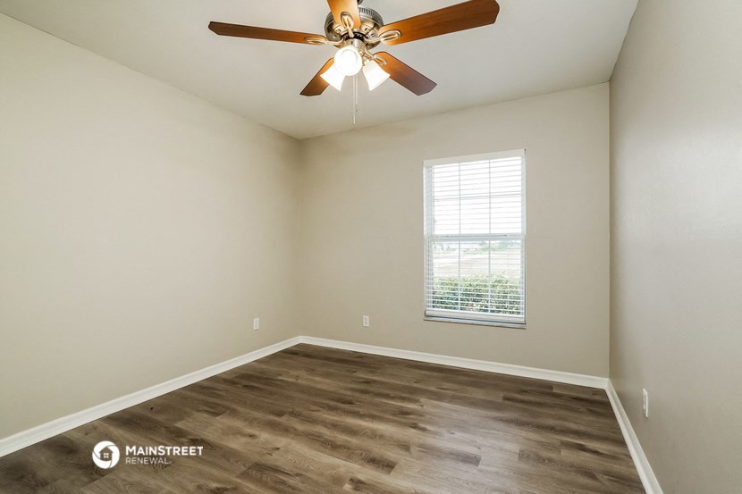 the spacious living room with a ceiling fan and a window