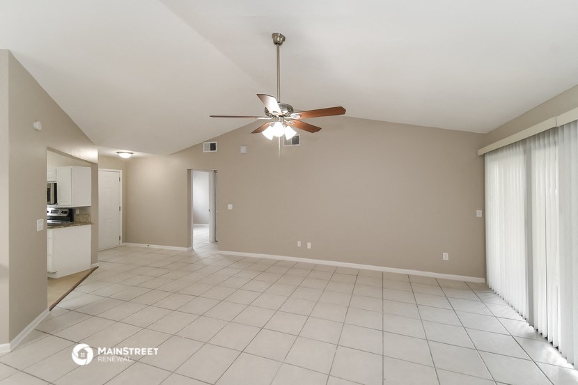 an empty living room with a ceiling fan and a tiled floor