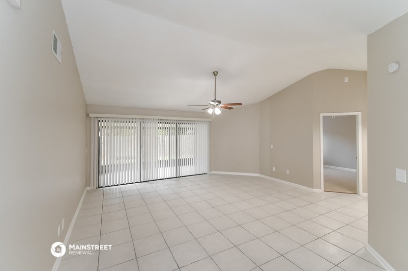 an empty living room with a ceiling fan and a window