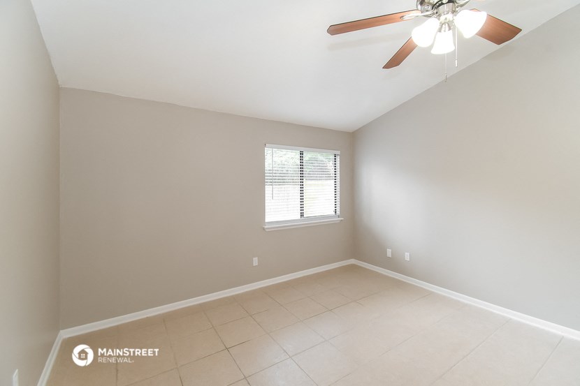 the spacious living room with ceiling fan and tiled floor