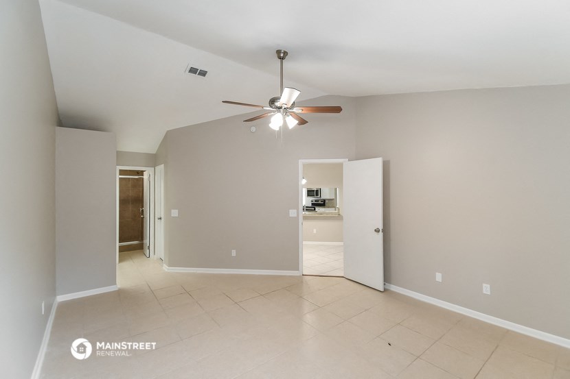 the spacious living room with ceiling fan and tiled floor